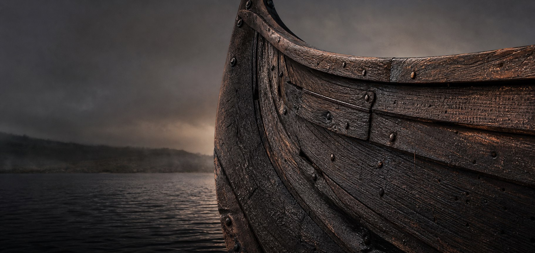 Dark wooden Viking-style longboat bow on the water